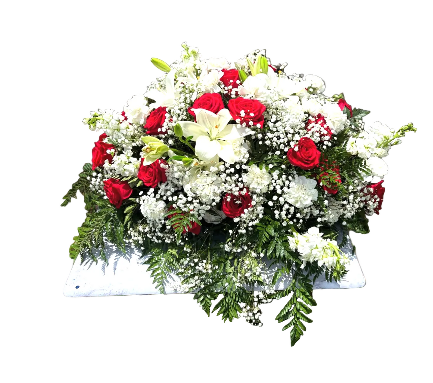 spray arrangment of red and white flowers on a stand against a brick wall.