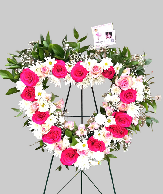 Heart-shaped floral arrangement with pink and white flowers on a brick wall background
